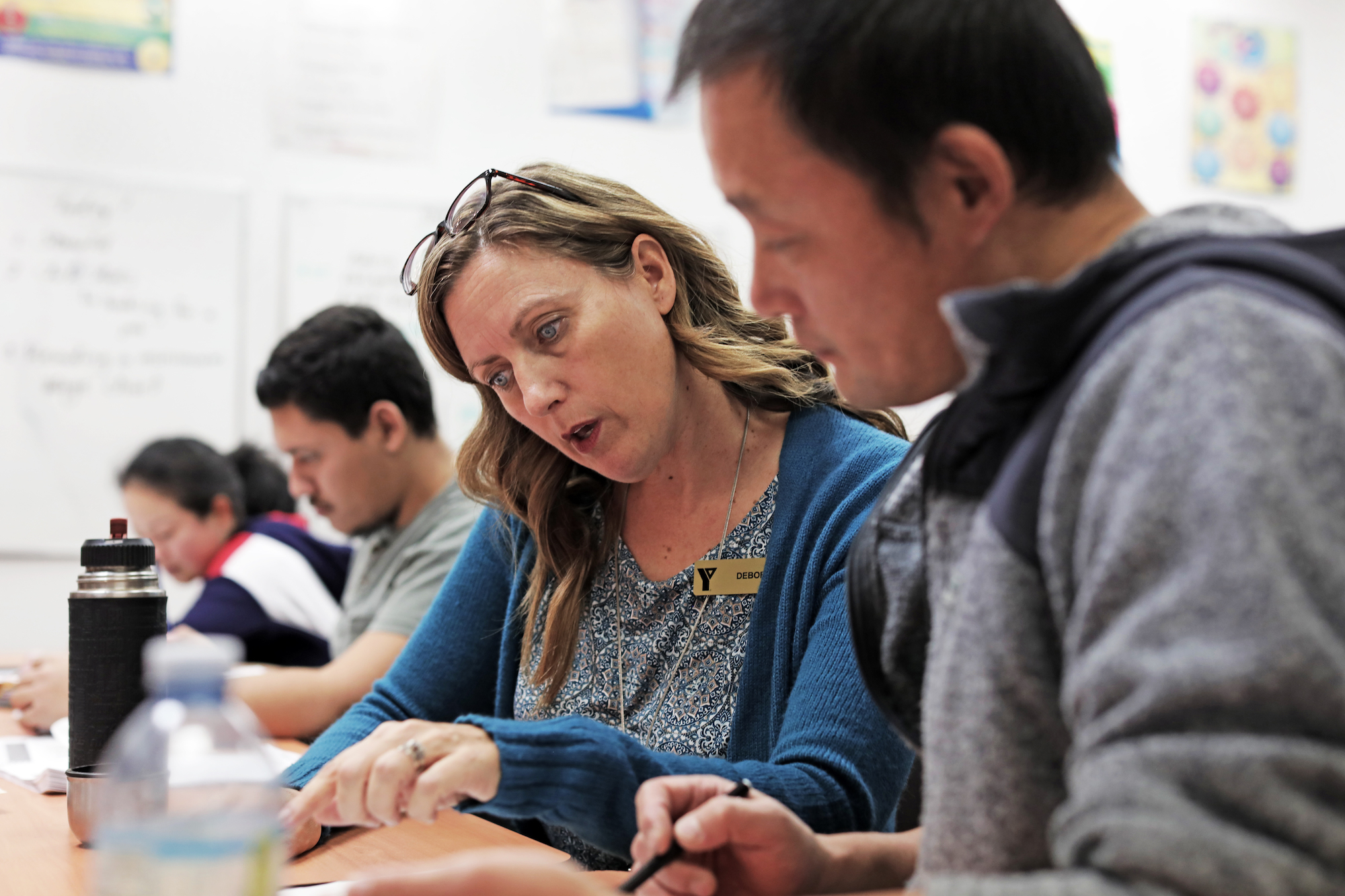 A YMCA language instructor coaches a student in a group class.