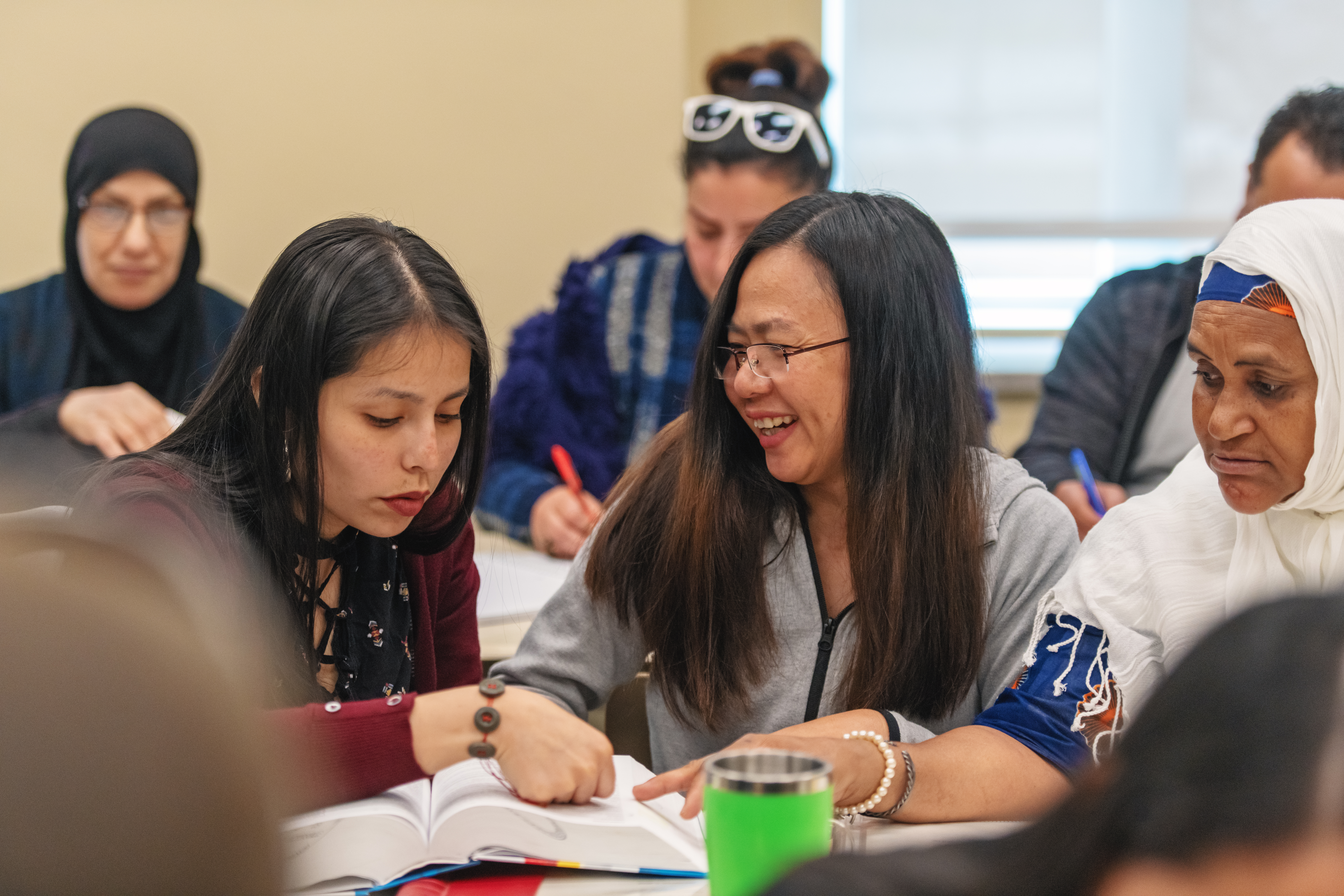 Three ladies work together to translate words in a dictionary.