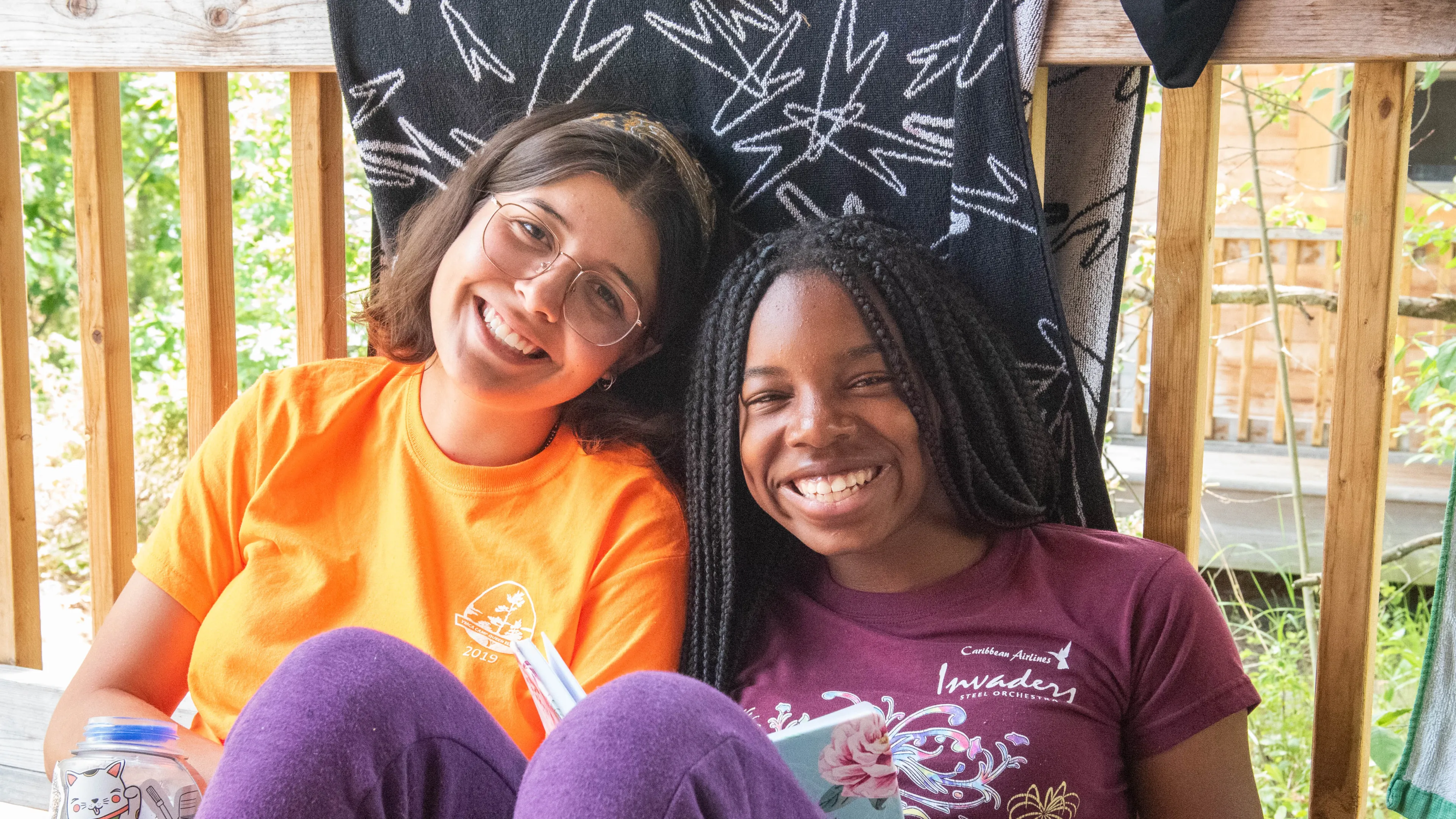 CQE Camp Counselor and Camper sitting on their cabin porch during free time.