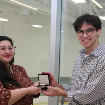 smiling woman with presenting a medal to a taller man 